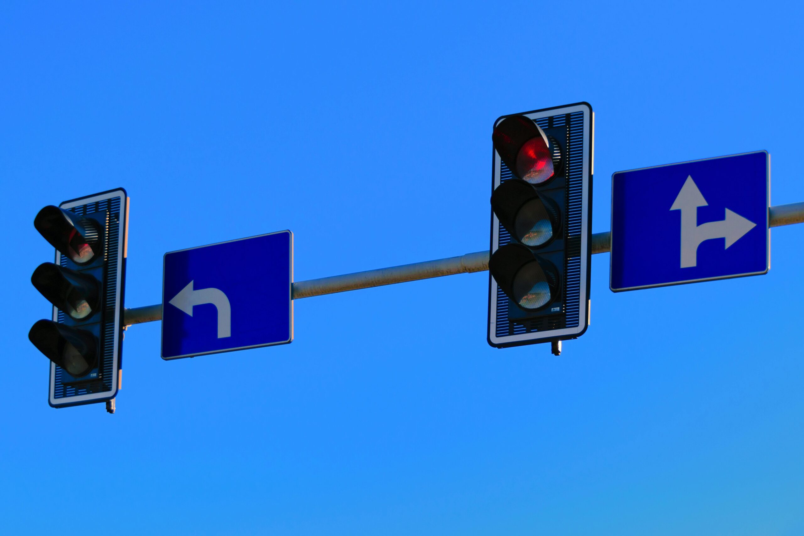 Traffic lights and directional road signs on a clear day with blue skies.